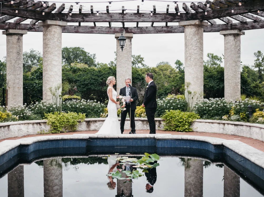 Wedding ceremony under an outdoor pergola with guests seated on either side at The Pavilion